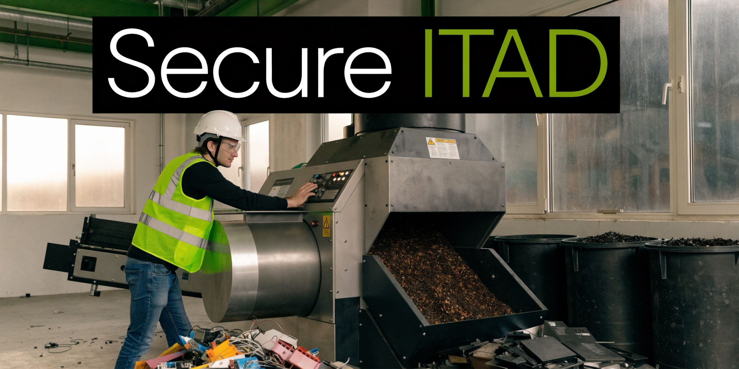 A worker in a high-visibility vest and hard hat operating an industrial electronic waste shredder machine.