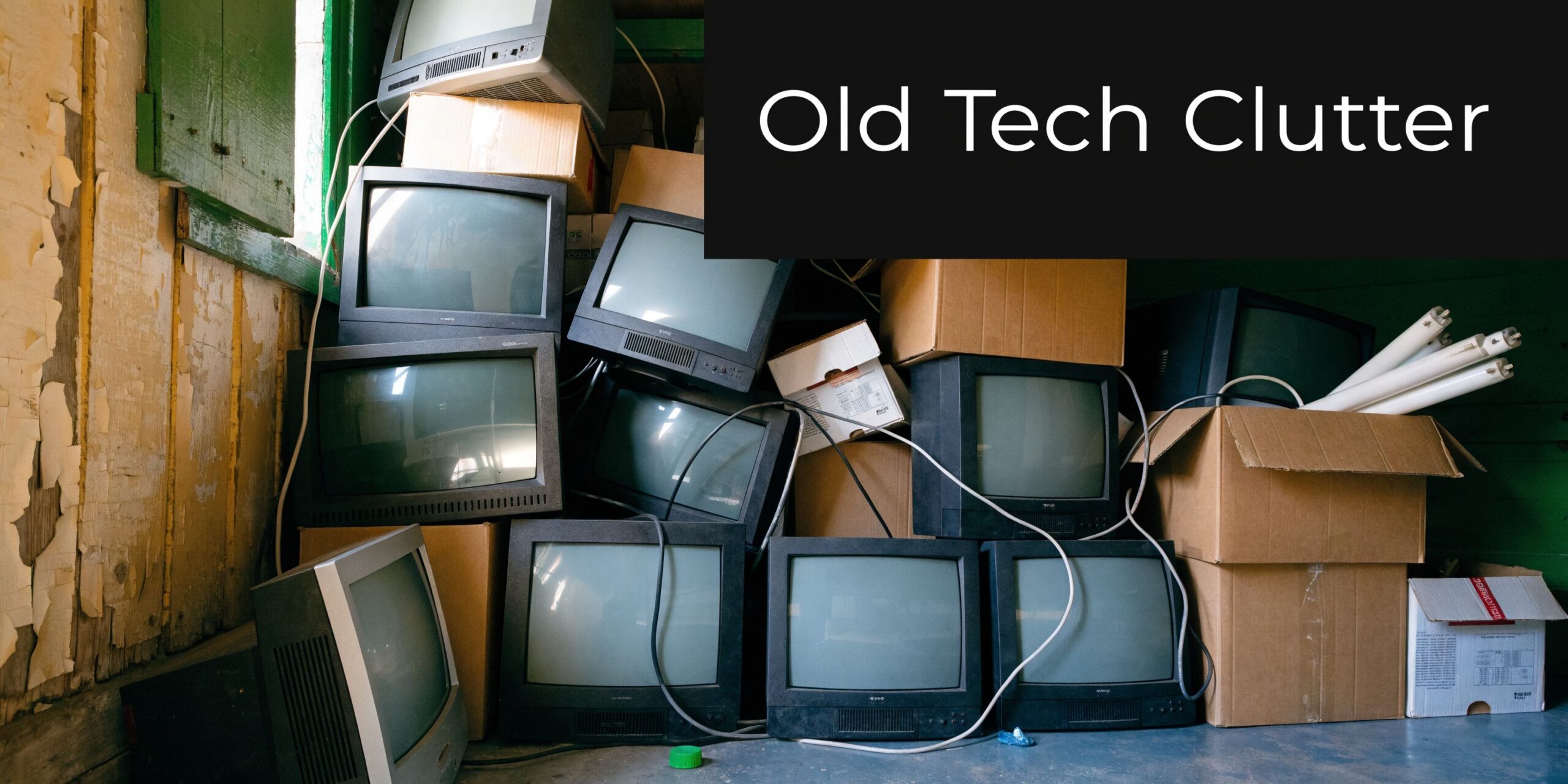 A pile of discarded old cathode ray tube television sets stacked inside a cluttered storage room area.